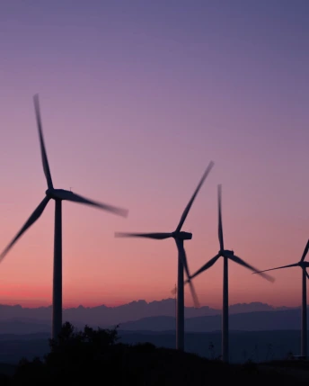 Turbinas eólicas al atardecer en un parque eólico que simboliza el uso de energías renovables